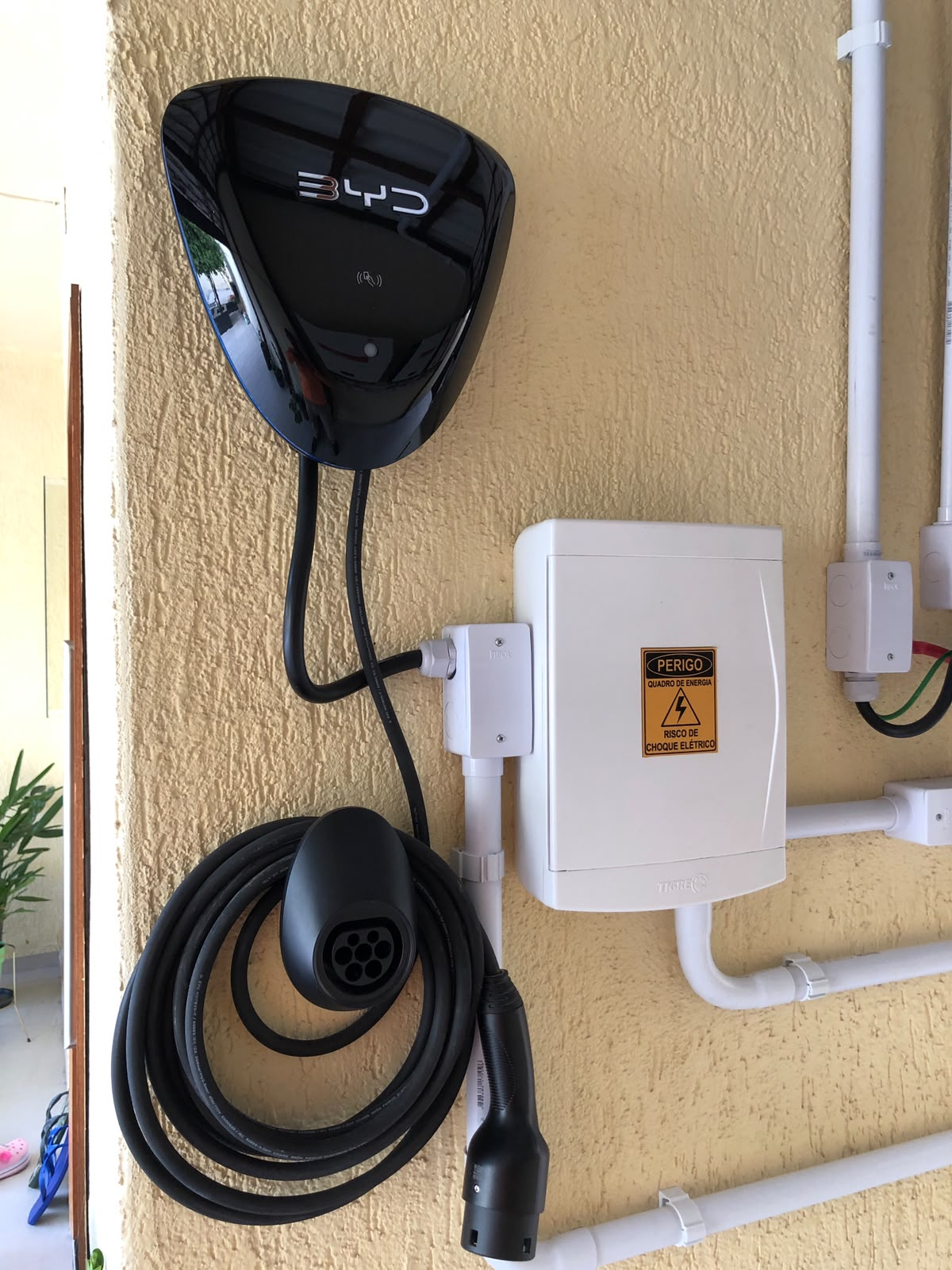 Carregador BYD instalado em parede, com quadro de proteção e cabo de recarga