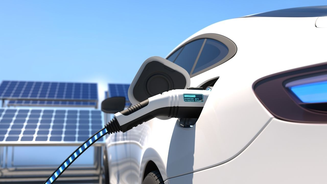 Veículo elétrico conectado a carregador com painéis solares ao fundo