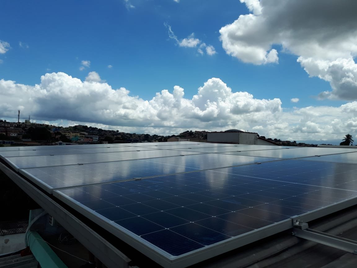 Painéis solares instalados em telhado, sob um céu ensolarado
