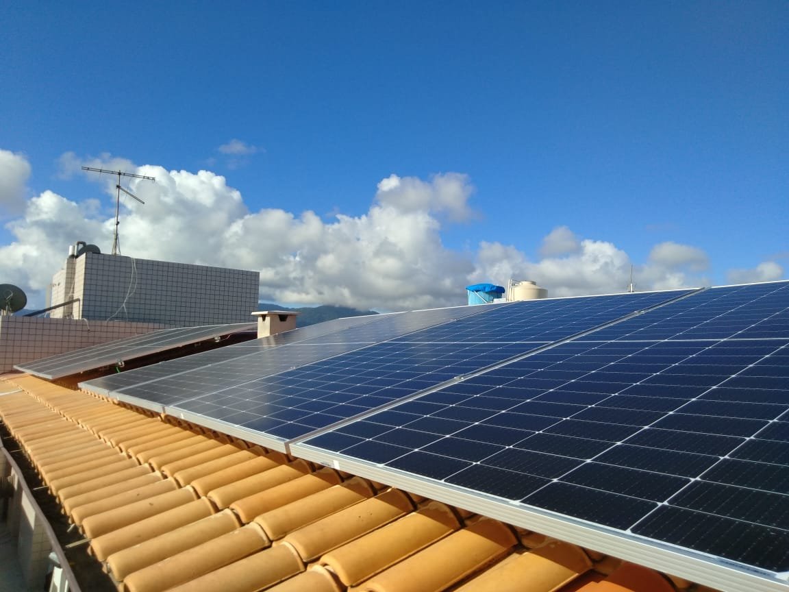 Painéis solares instalados em telhado residencial sob céu azul